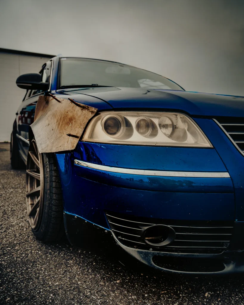 Front view of a lowered blue car with a metal wing and low front bumper.