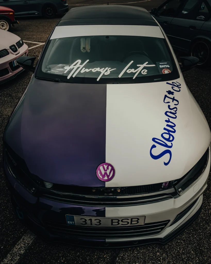 Volkswagen with a purple and white bonnet and Always late lettering across the windscreen.