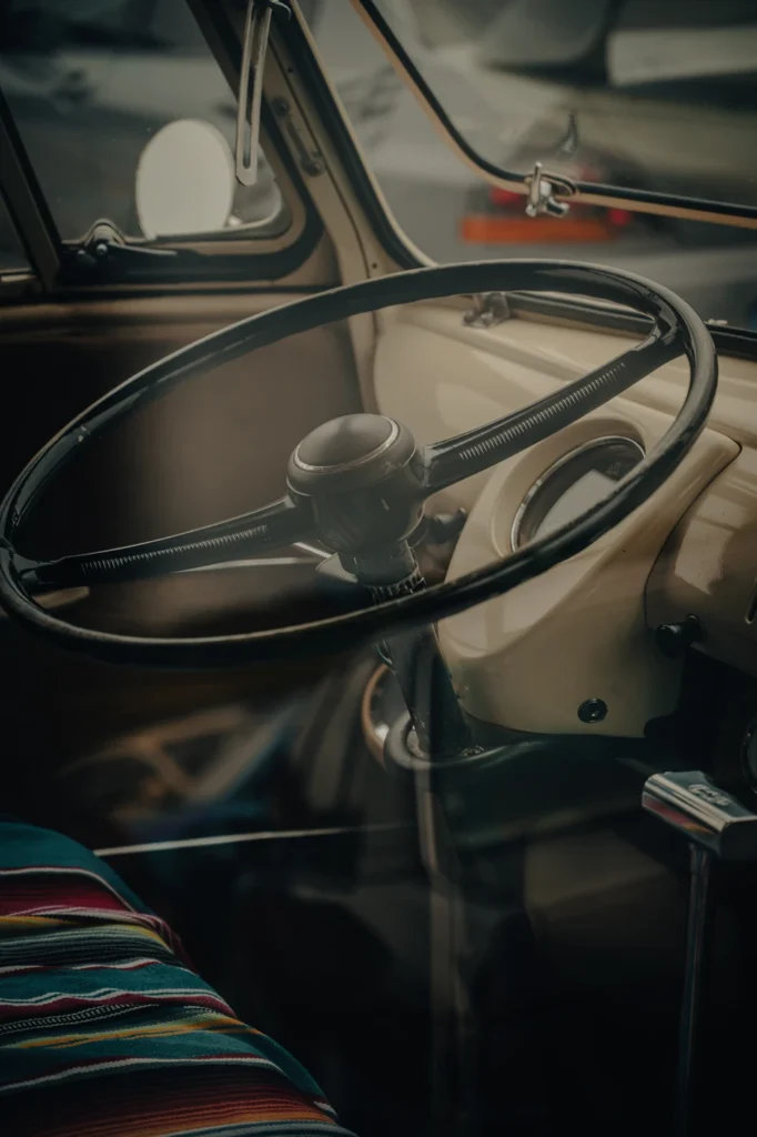 Black steering wheel, pale dashboard and striped seat in a vintage Volkswagen van.