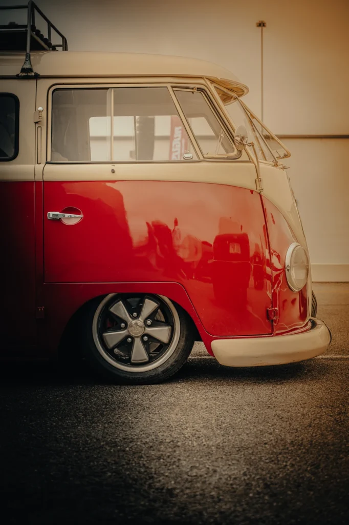 Side view of the front of a lowered red and beige Volkswagen van in warm light.