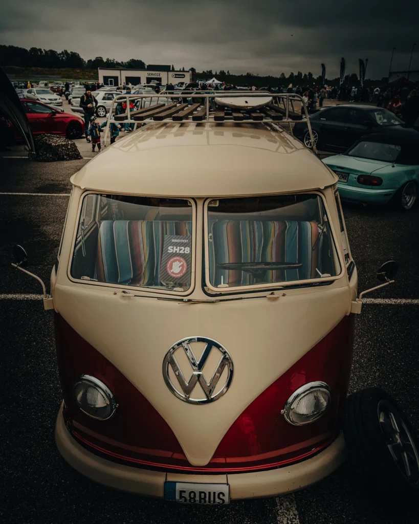 Red and beige Volkswagen van viewed from above, with striped seats and a roof rack.
