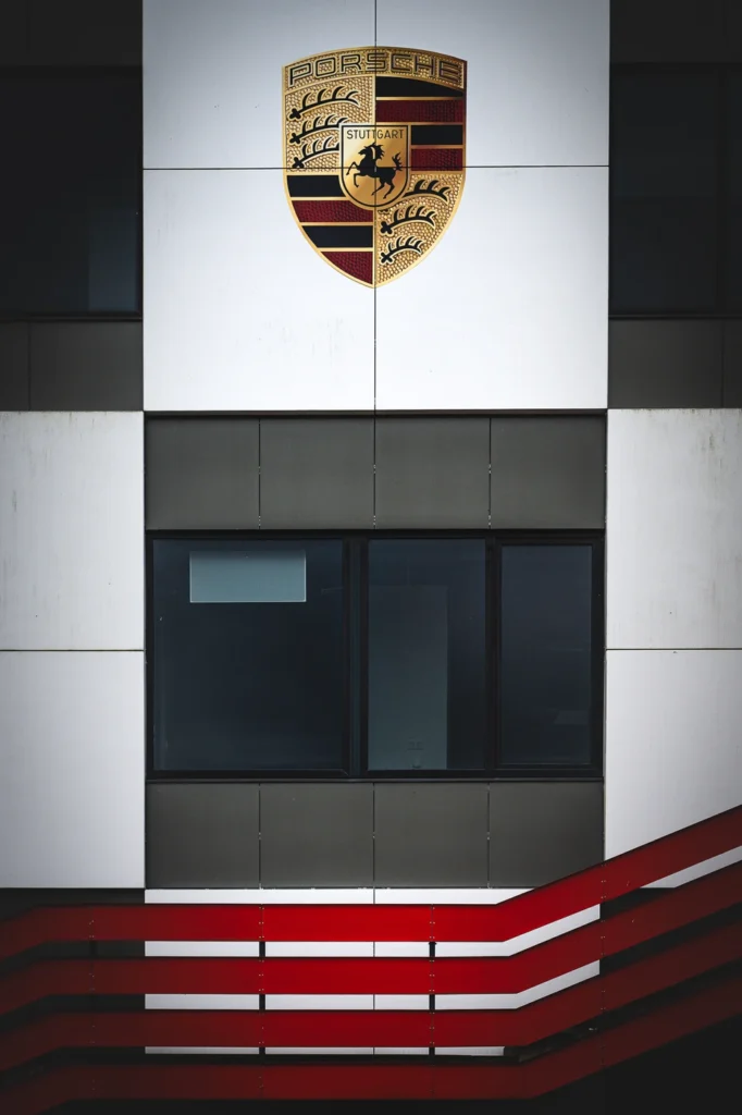 Porsche crest on a silver facade above red horizontal panels.
