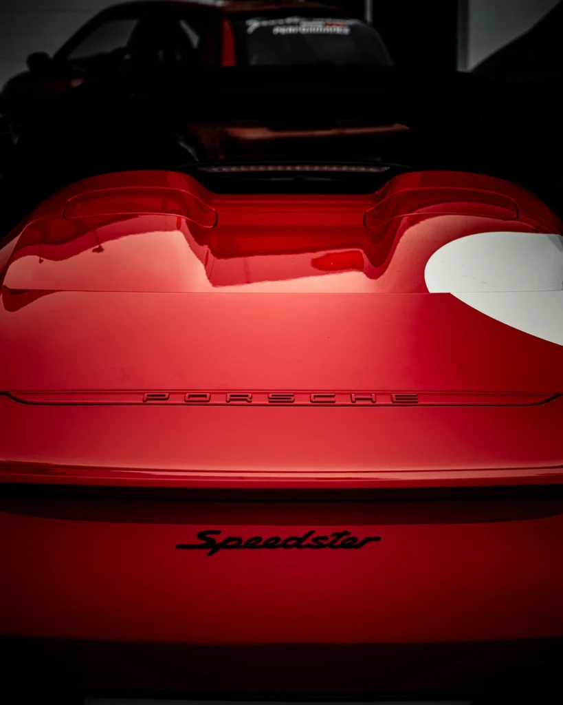 Rear of a red Porsche with Speedster lettering and a white circle on the glossy bodywork.