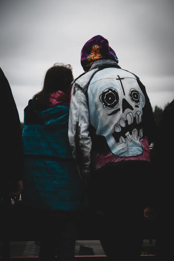 Two festival visitors seen from behind, one wearing a jacket with a large skull on the back.