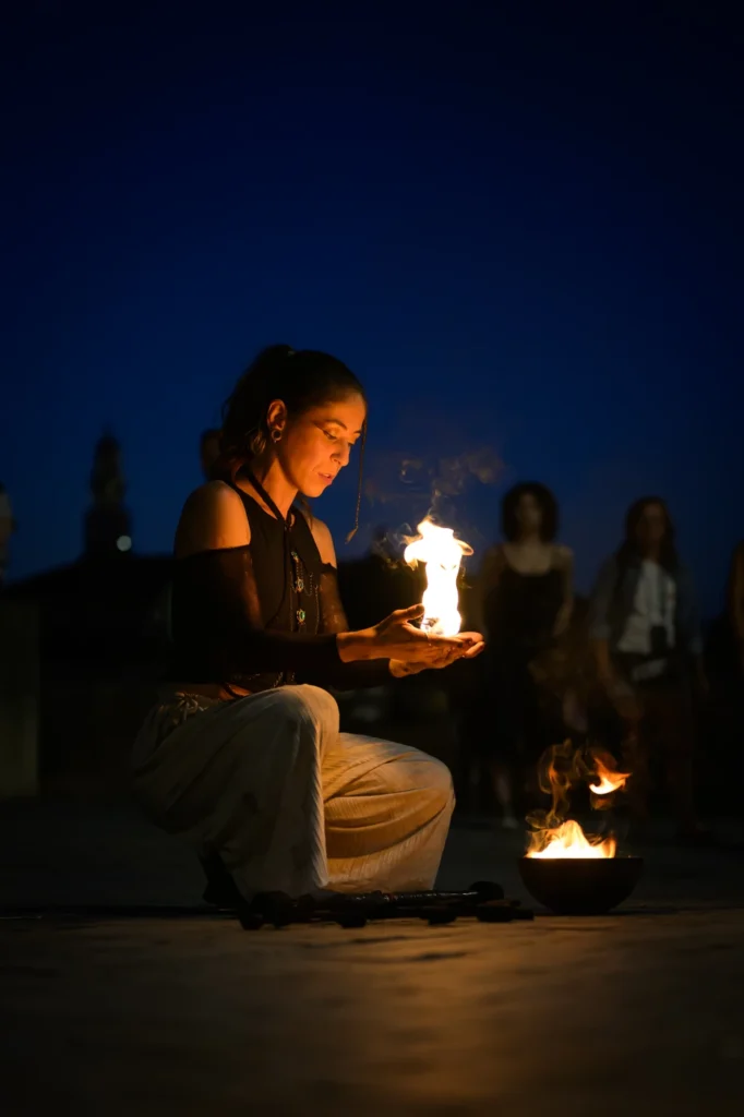 Fire performer holding flames at dusk.