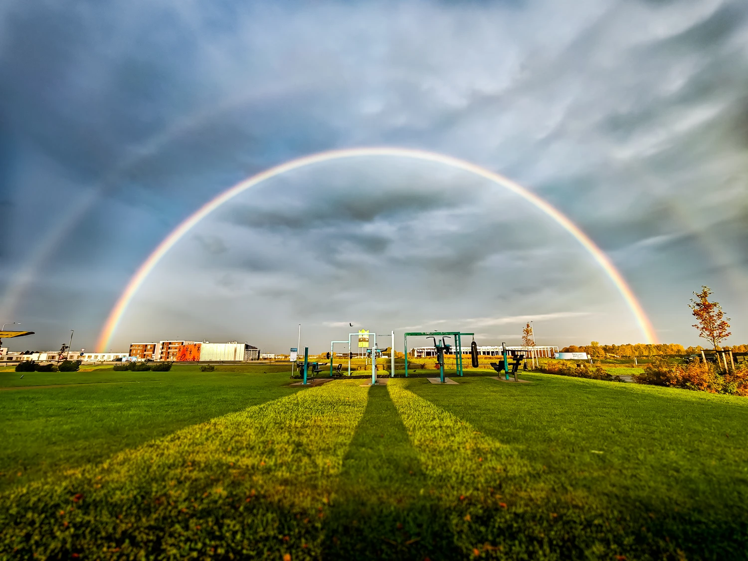 Full rainbow over green field with long morning shadows, Tartu (Täispärlike vikerkaar rohelise väljaku kohal, pikad hommikuvarjud, Tartu)