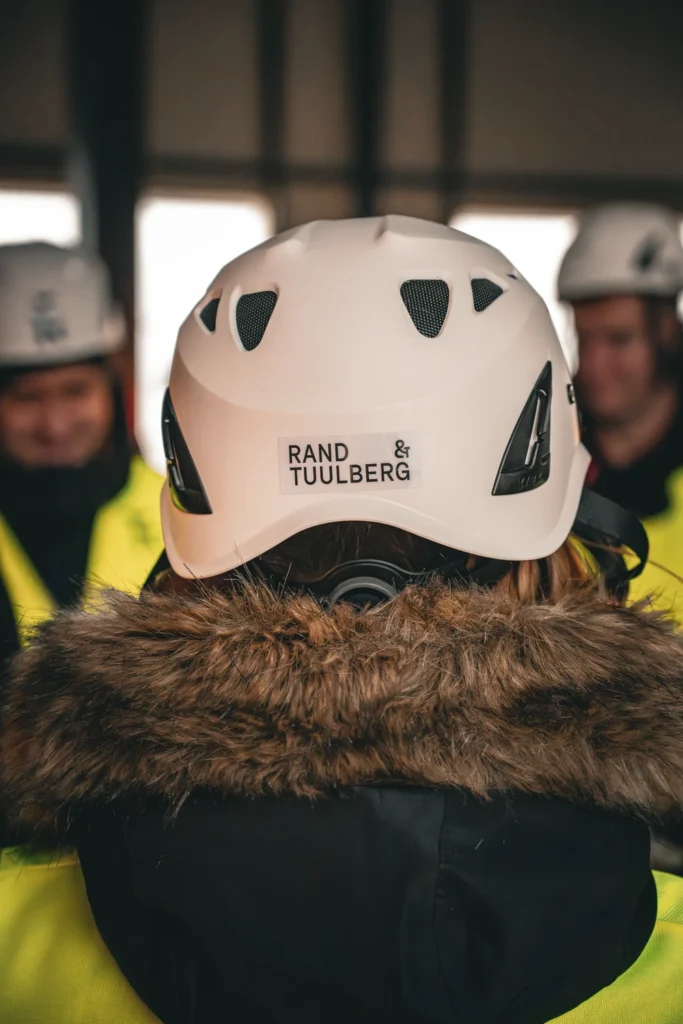 Close-up of a white hard hat bearing the Rand & Tuulberg name above a fur-trimmed hood.