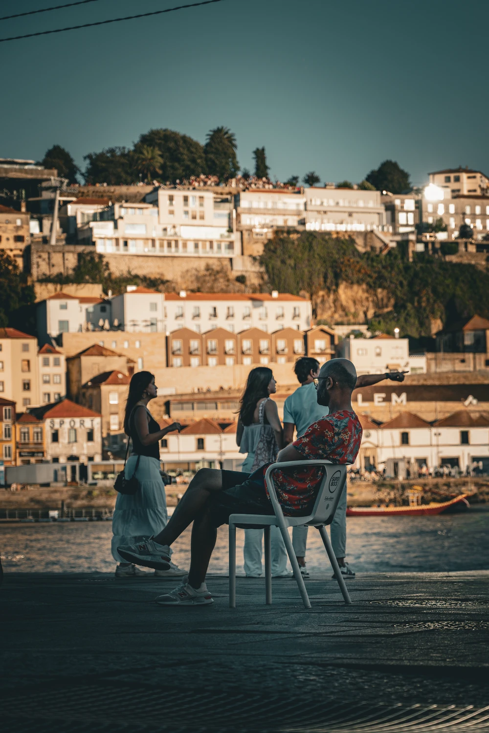 People sitting by the Douro River in Porto, cityscape in the background