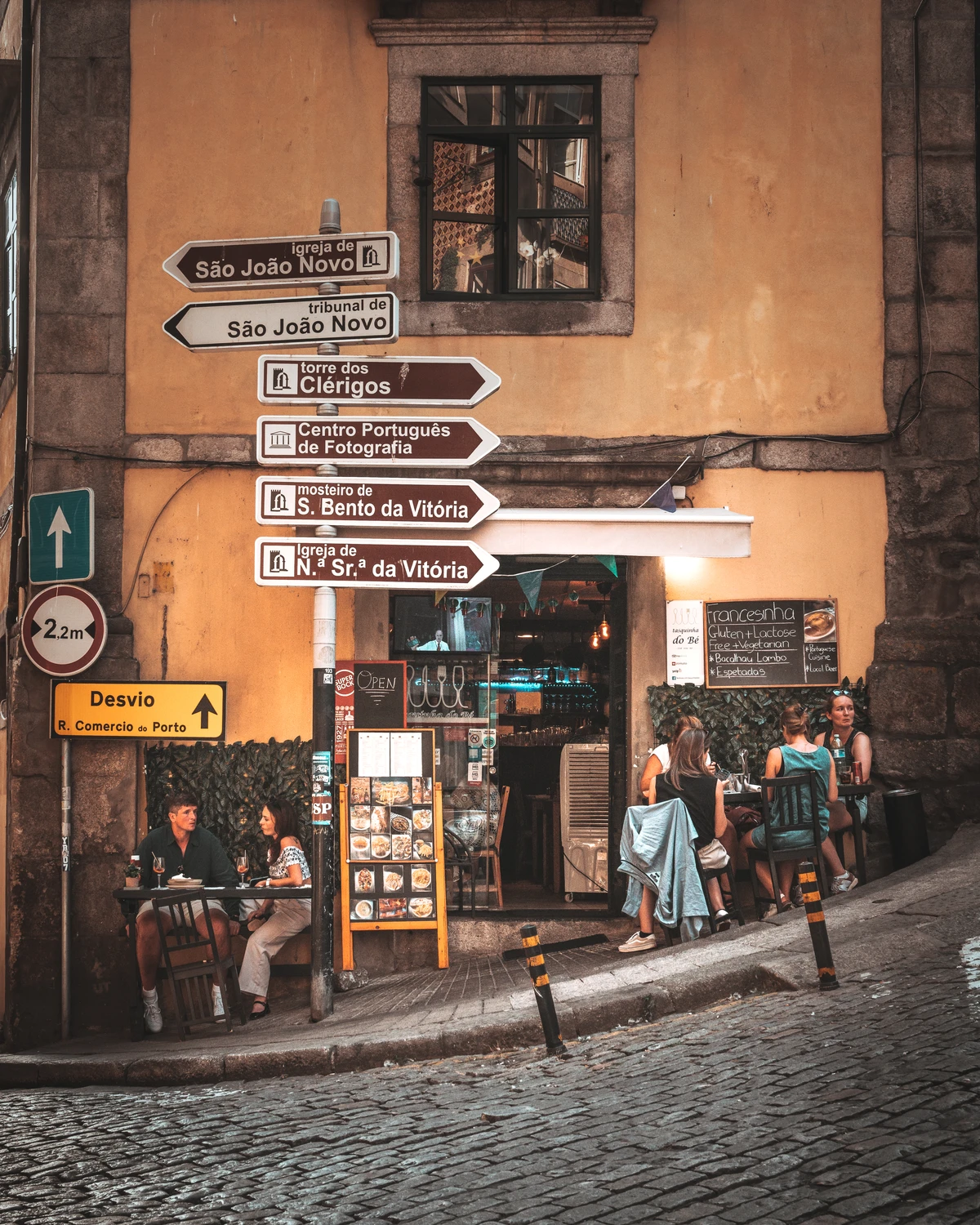 Street corner café in Porto with directional signposts and evening atmosphere