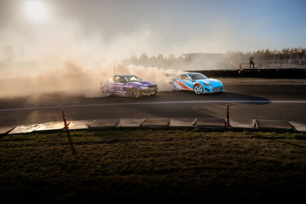 A purple drift car and a blue car with a large rear wing corner together.
