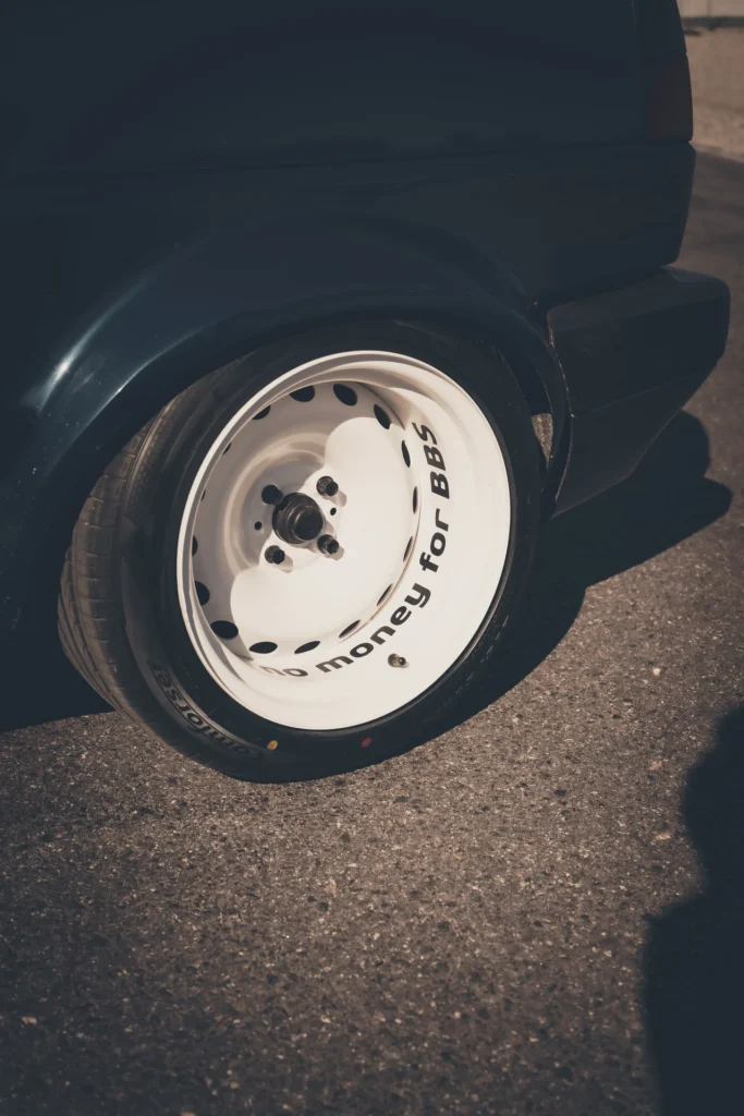 Close-up of a dark car's white steel wheel with black lettering.
