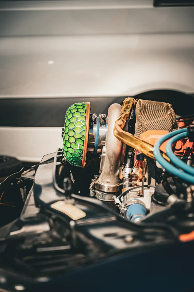 A green honeycomb-pattern air filter and metal pipes in a racing car's engine bay.