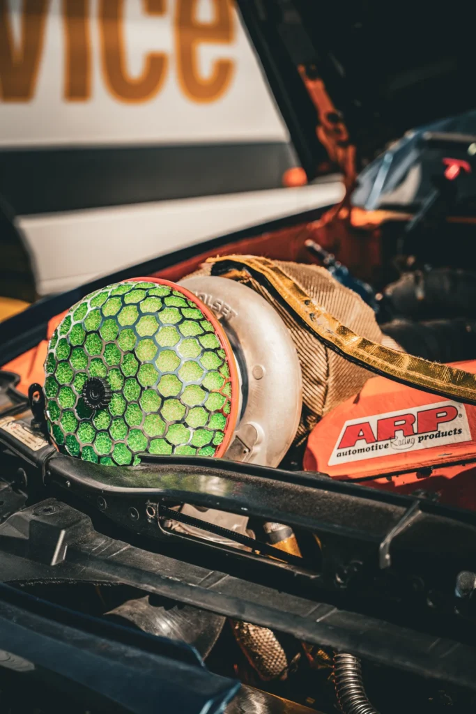 Close-up of a green air filter beside a heat-wrapped component in an engine bay.