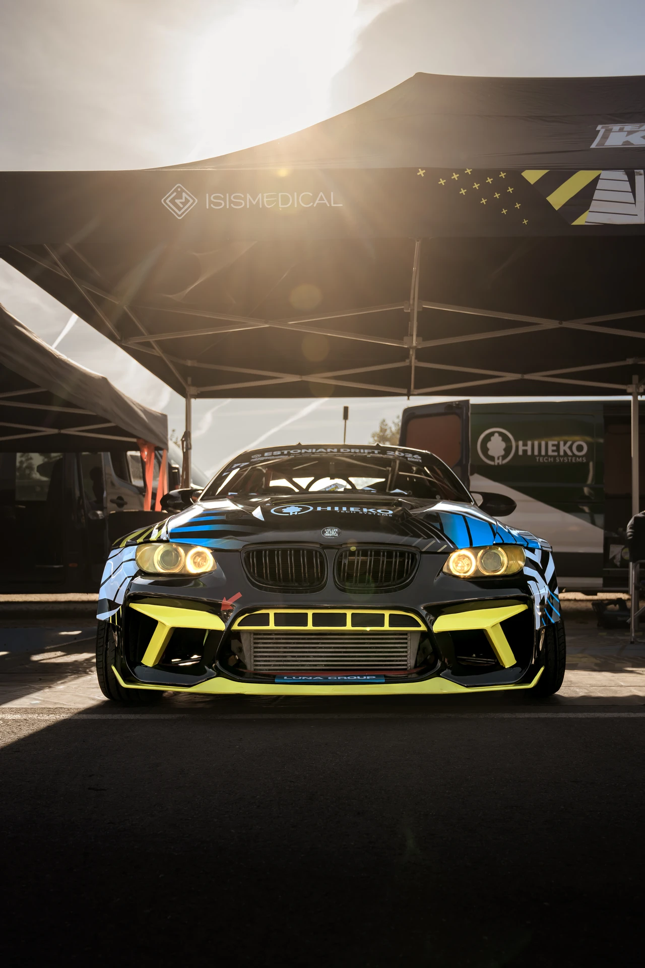Yellow drift car front view under paddock lights.