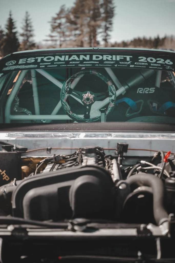Front view of a drift car with its bonnet removed, showing the steering wheel and light-coloured roll cage.