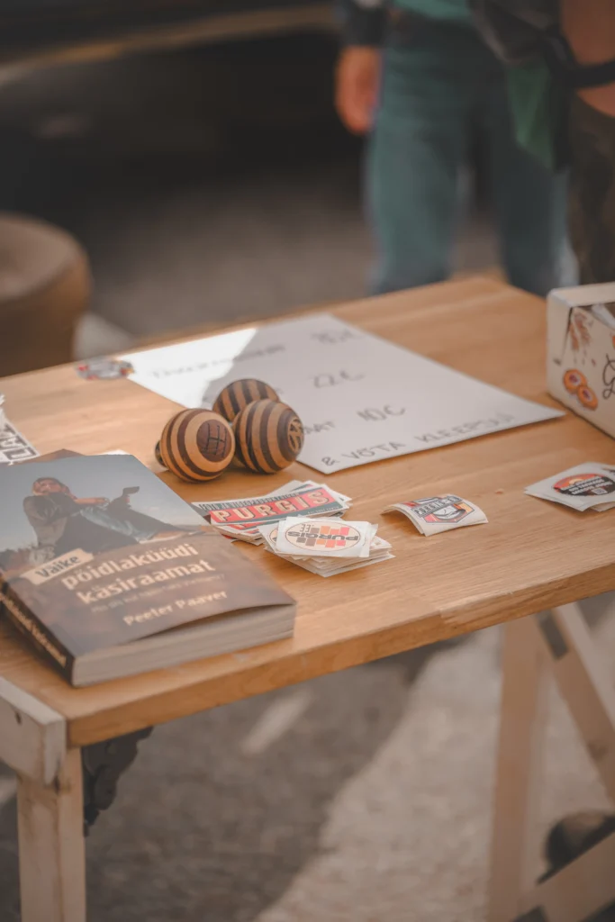 Striped wooden gear knobs, stickers and an Estonian hitchhiking handbook on a wooden table.