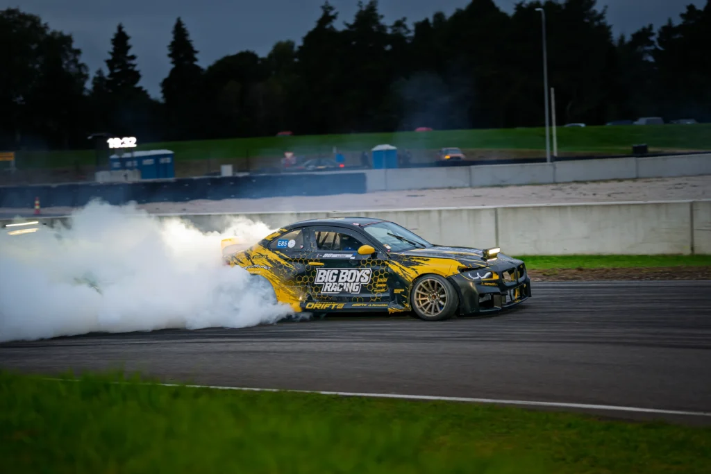 Mustkollase auto tagaratta juures helendab suits, esiplaanil roheline mururiba.