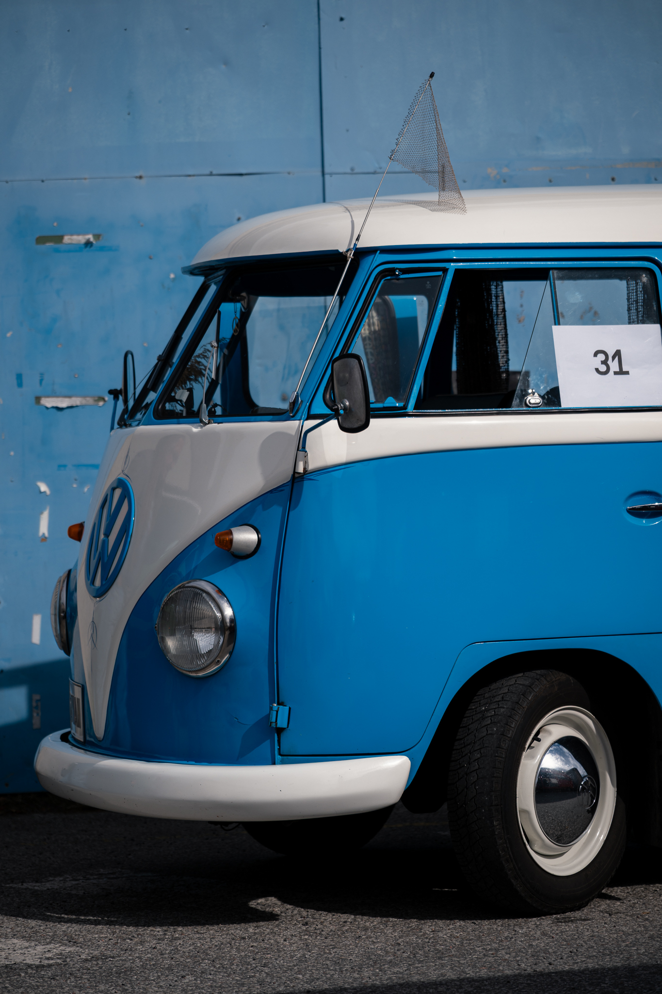 Sinivalge Volkswageni matkabuss sinise seina ees päikesevalguses.