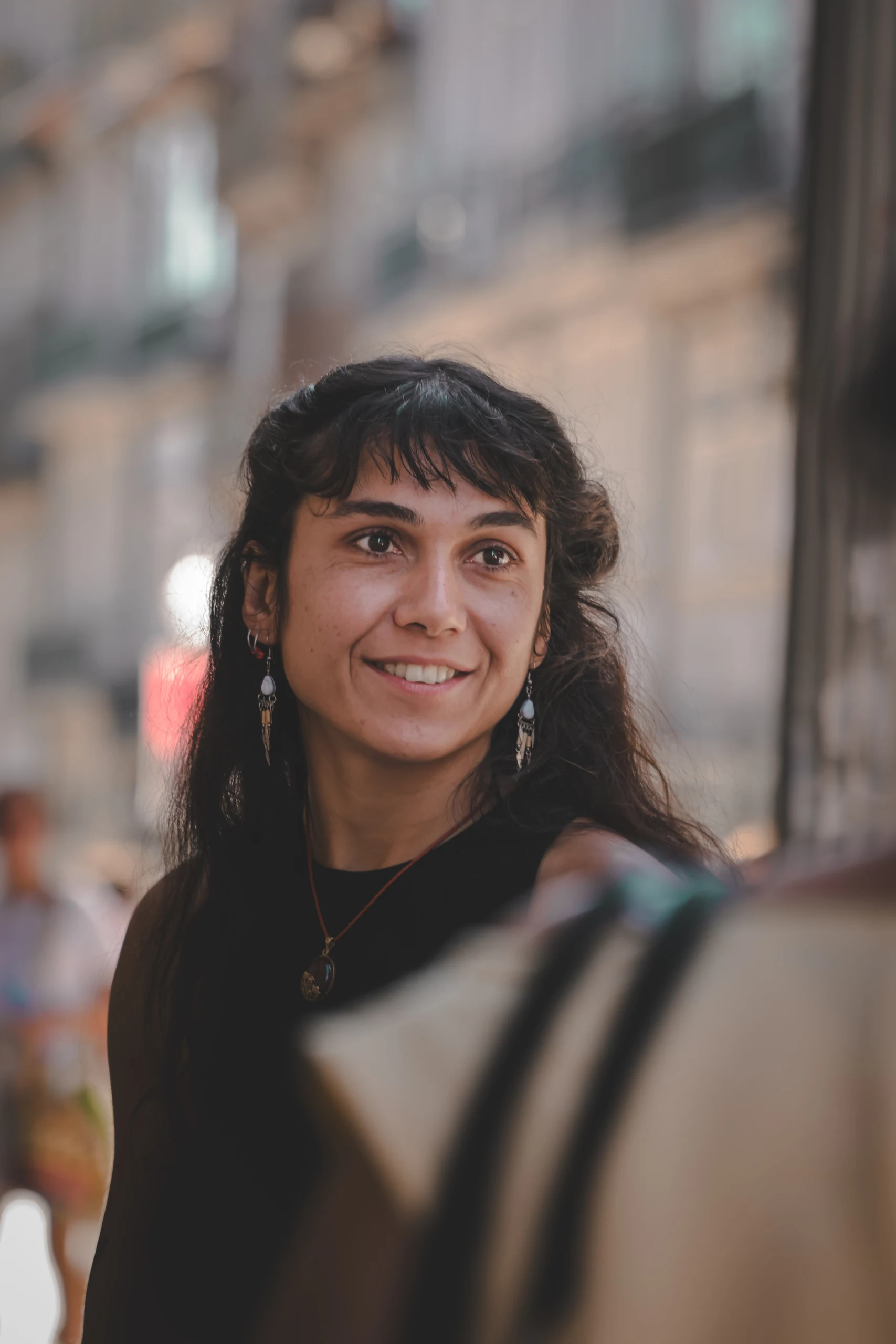 Gökçe naeratab Porto tänaval, taustal pehmelt hägustunud hooned.