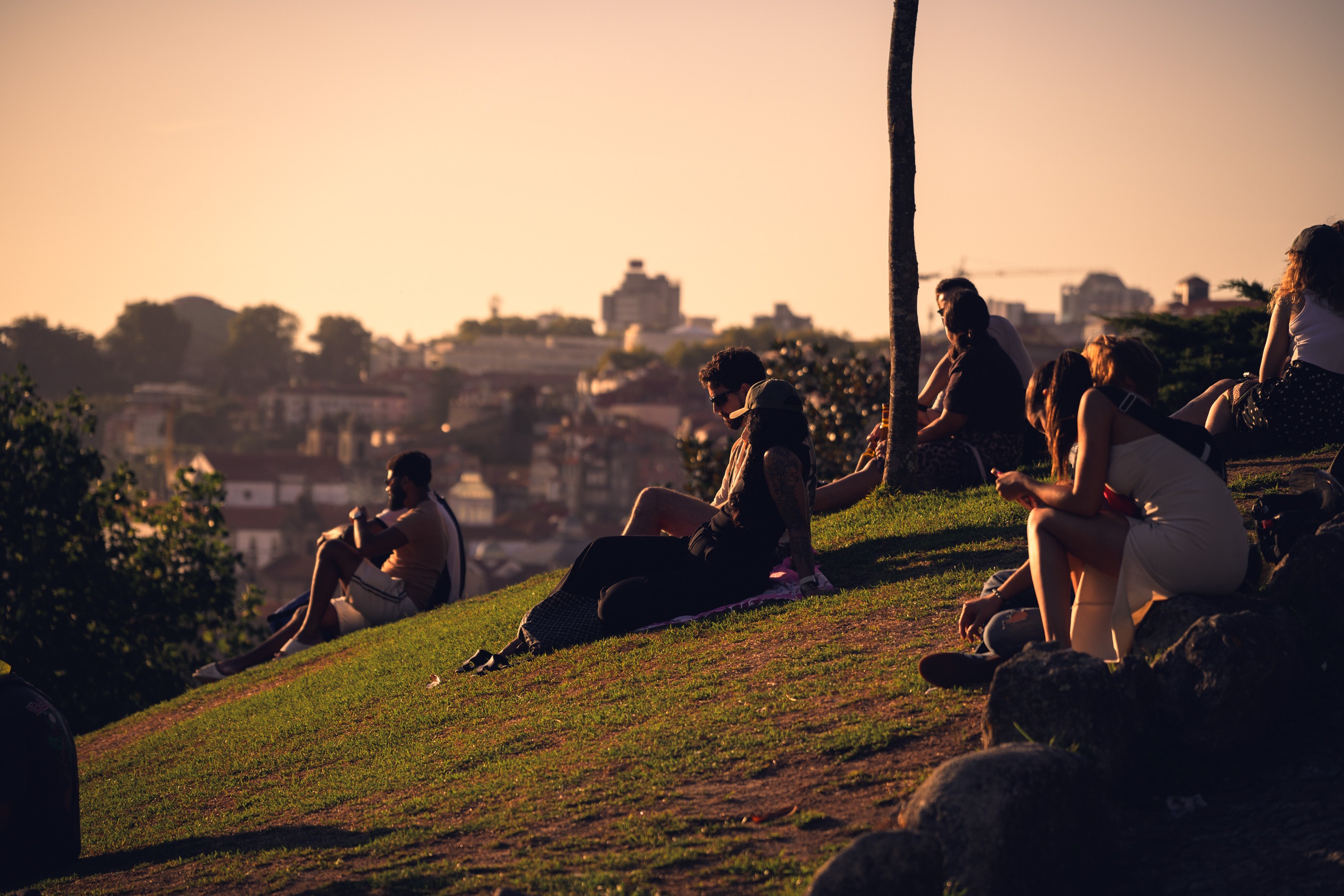 With preset. People on the Jardim do Morro hillside with warm evening light on faces — with the Golden Hour Skin preset.