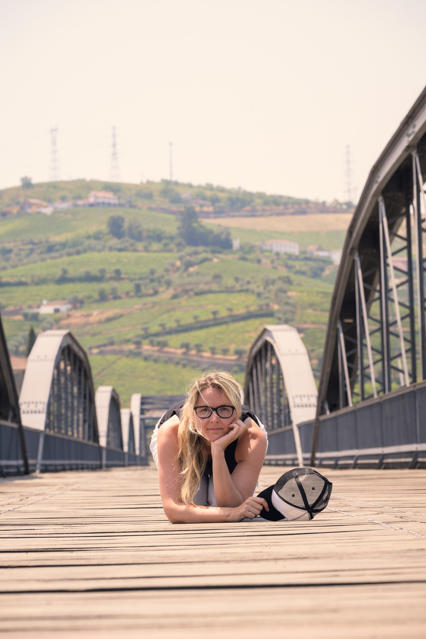 With preset. Woman on a Douro footbridge below a bright sky in direct sun — with the Hard Sun Control preset.