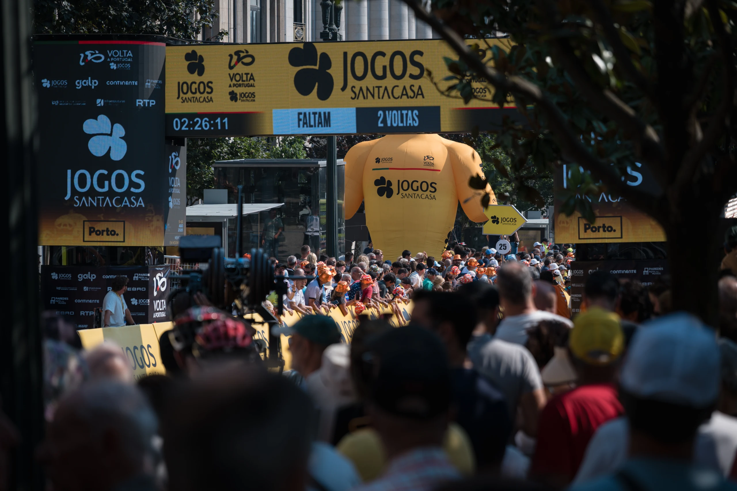 Spectators beneath the yellow Volta a Portugal finish arch in central Porto.