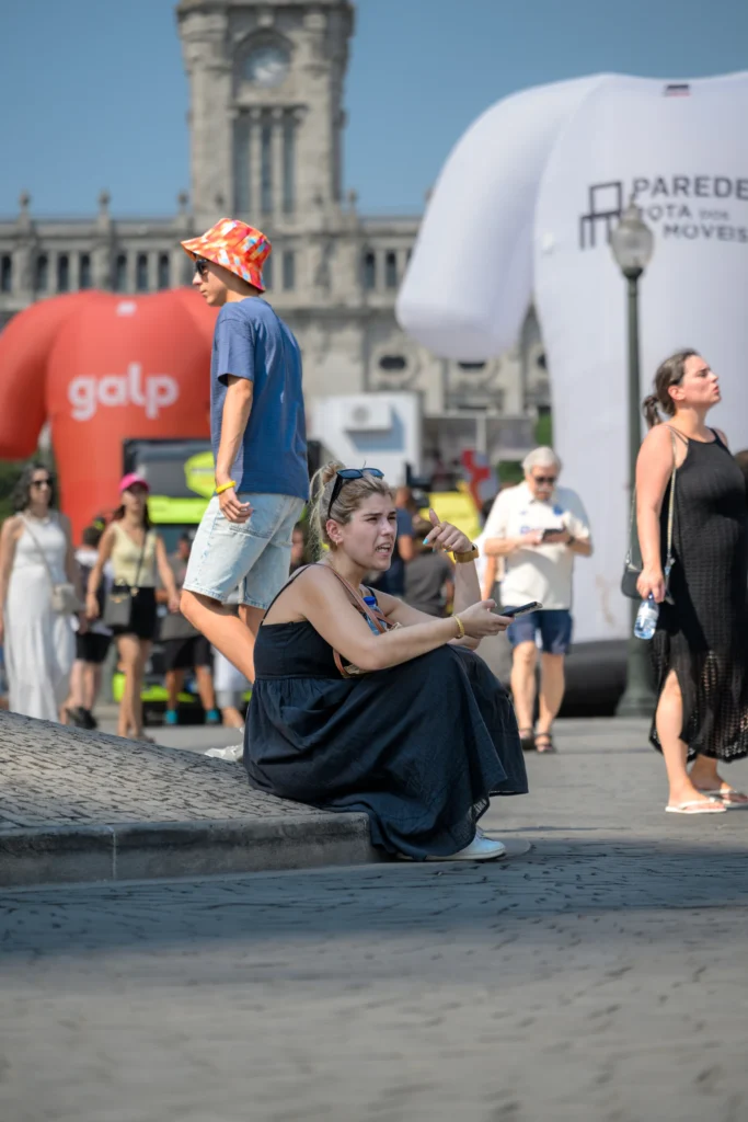 A woman sits beside the road among spectators waiting for the cycling race.