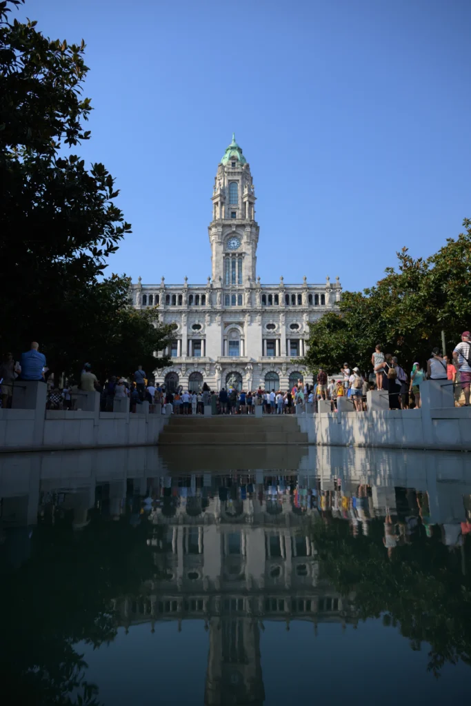 Porto city hall and a blue sky are reflected in the water on the square.